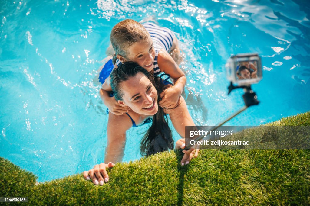 Happy family having fun in swimming pool ,taking photos and videos with waterpoof action camera