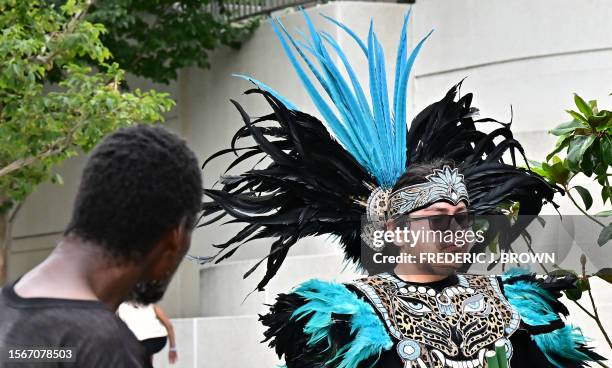 Homeless man looks at a member of Danza Azteca Tenochtitlan as they arrive to protest the confiscation of Native American feathers, in front of the...