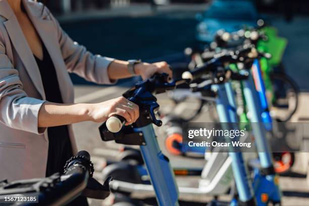 close-up of woman using shared electric scooter rental in the city - trotinete imagens e fotografias de stock