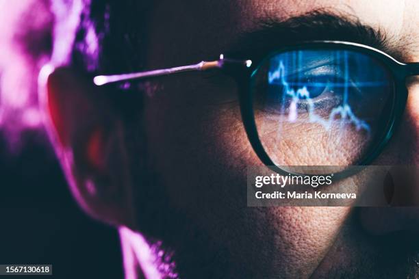 close-up portrait of man working on computer. сhart reflecting in glasses. data analytics statistics information business technology. - exchange stockfoto's en -beelden