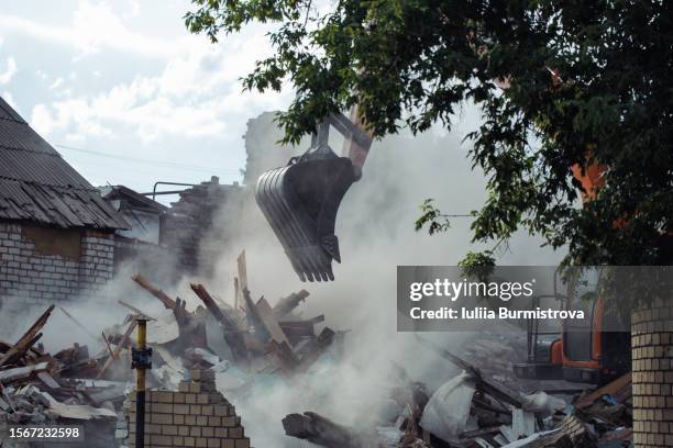 bulldozer just demolished old house and dust from wreckage enveloped working machinery. - dismantling stock pictures, royalty-free photos & images