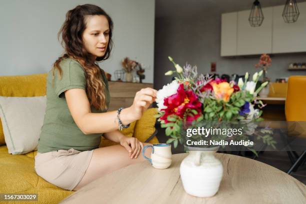 woman in a colorful living room with bouquet and tea - magnoliopsida bildbanksfoton och bilder
