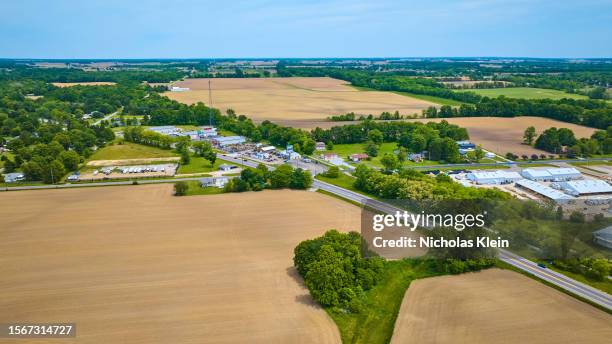 Aerial of small town with lots of barren fallow farmland and green trees