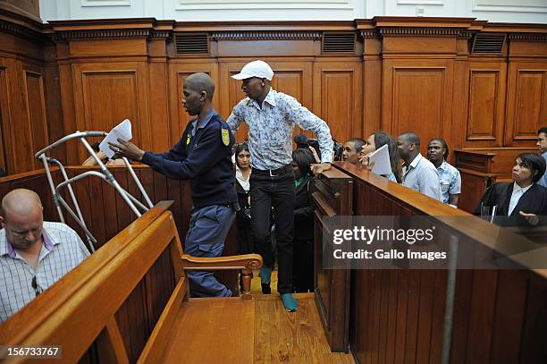 Xolile Mngeni is assisted by a police officer in the Cape Town High Court on November19, 2012 in Cape Town, South Africa. Mngeni was found guilty of...