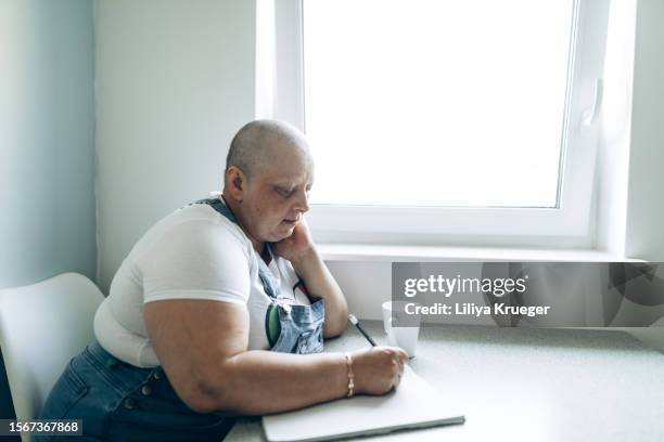 portrait of a woman with cancer sitting by the window. - chronic fatigue stock-fotos und bilder