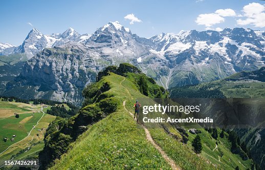 Trail runner ascends alpine path in Swiss mountain landscape