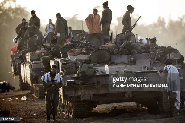 Israeli soldiers wearing "Talit" conduct morning prayers at an Israeli army deployment area near the Israel-Gaza Strip border on November 20 as talks...