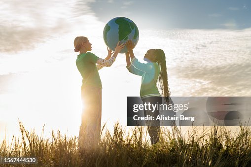 Two female eco activists holding up a hand painted globe Two female eco activists holding up a hand painted globe