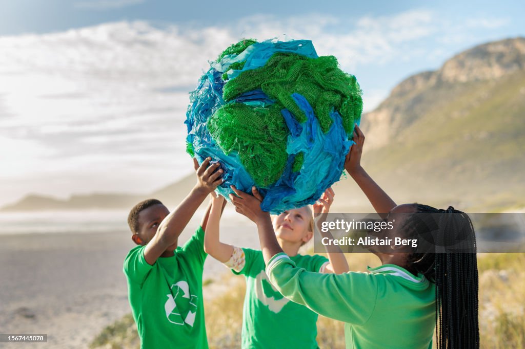 Group of young climate activists holding up a globe together by the sea