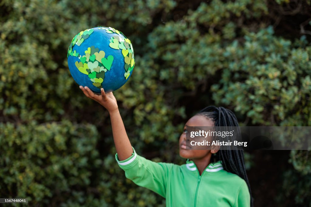 Young African girl holding up a homemade globe of green heart shapes