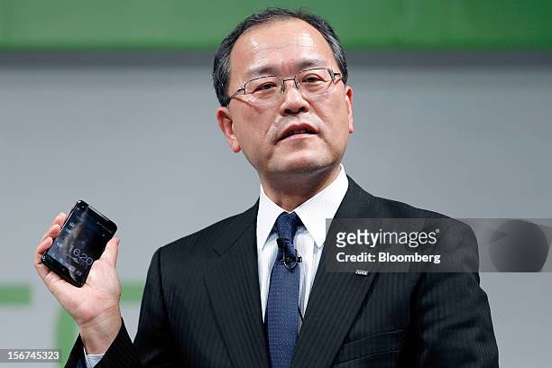 Takashi Tanaka, president of KDDI Corp., holds the HTC J Butterfly smartphone, produced by HTC.Corp., during the unveiling event in Tokyo, Japan, on...