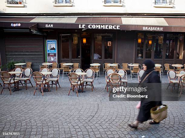 Pedestrian walks past empty tables outside the Le Commerce cafe in Paris, France, on Tuesday, Nov. 20, 2012. France's government bonds fell, with...