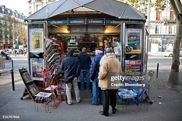 Customers stand in line as they wait to be served outside a news kiosk in Paris, France, on Tuesday, Nov. 20, 2012. France's government bonds fell,...