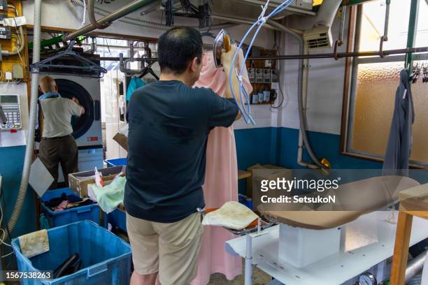 family business, asian dry cleaners. senior owner and adult son. - man washing basket child stock pictures, royalty-free photos & images