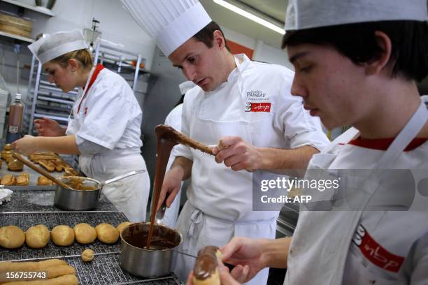 Teacher explains how to glaze an eclair au chocolat at the National Bakery and Pastry Institute on November 20, 2012 in the northwestern city of...