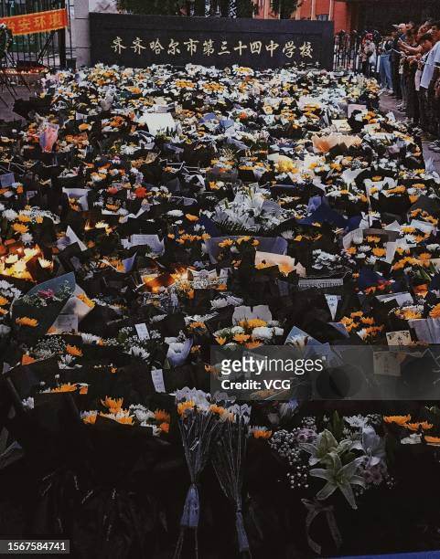 People lay flowers outside a middle school after the roof of a school gymnasium collapsed on July 24, 2023 in Qiqihar, Heilongjiang Province of...