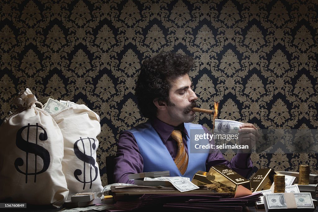 Adult man sitting lighting cigar with burnt dollar bill