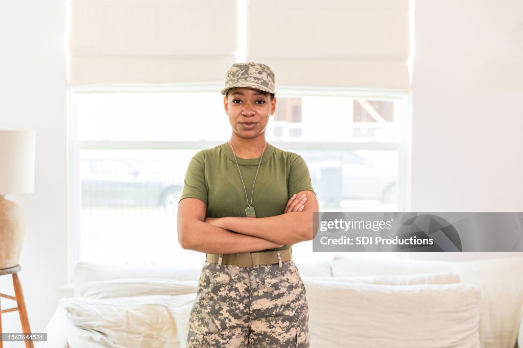 Proud female military service member stands with her arms crossed to have her photo taken