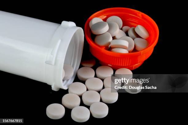 blank medicine bottle with spilled pills isolated on white background - steroid stock-fotos und bilder