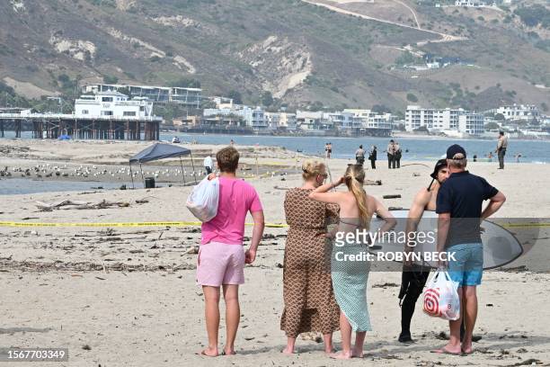 Beachgoers look past police tape towards a barrel where a body was discovered in Malibu Lagoon State Beach, California on July 31, 2023. A body...