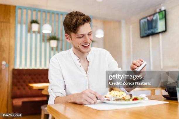 smiling young man eats a delicious meal in the restaurant with a salt - salt shaker stock pictures, royalty-free photos & images