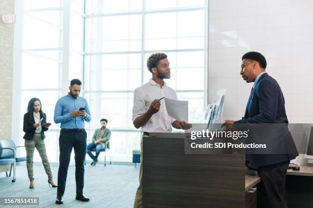 young man asks male banker questions about new account - bank teller stock pictures, royalty-free photos & images