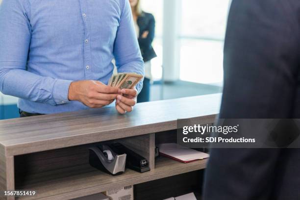 unrecognizable man double checks cash amount after bank withdrawal - bank counter stock pictures, royalty-free photos & images