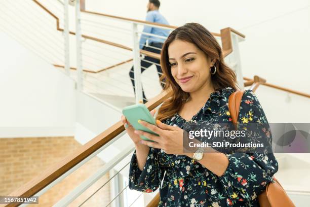 empresária sorri ao descer escadas e mandar mensagens ao telefone - cooperativa de crédito - fotografias e filmes do acervo
