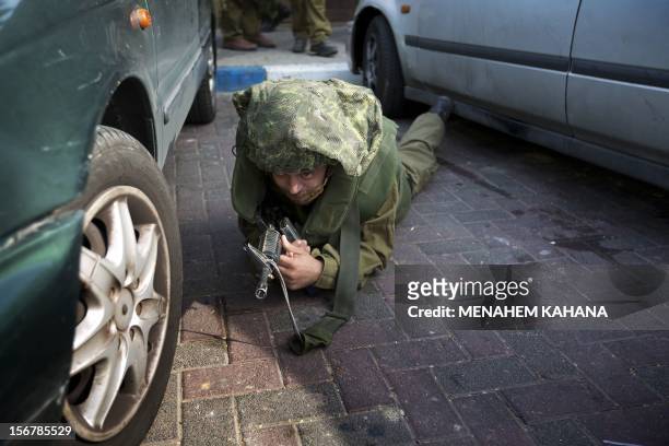 An Israeli soldier lies on the ground as he takes cover during a rocket attack from Palestinian militants in the Gaza Strip on 21 November 2012 at...