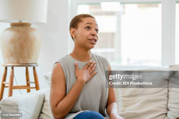 with hand on chest, woman shares honestly with unseen therapist - hands on chest stock pictures, royalty-free photos & images