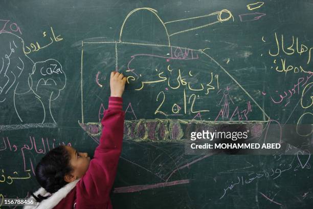 Palestinian girl writes on a blackboard inside a classroom where displaced families are staying after evacuating their homes earlier this week to...