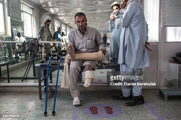 An Aghan man sits holding his prosthetic limb as he waits for a fitting with a specialist at the International Committee of the Red Cross orthopedic...