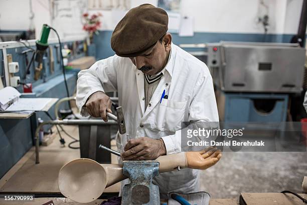 An orthopedic technician works on a prosthetic arm at the International Committee of the Red Cross , orthopedic centre on November 20, 2012 in Kabul,...