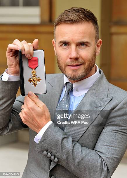 Gary Barlow holds his OBE, for services to the entertainment industry and to charity, which was awarded to him by Queen Elizabeth II during an...
