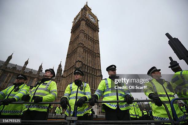 Police officers stand guard in front of the Houses of Parliament as students protest against the rising costs of further education on November 21,...