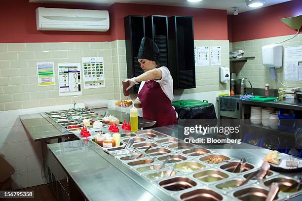 An employee prepares a customer's sanwdwich order in the kitchen of a 100 Montaditos restaurant in Madrid, Spain, on Wednesday, Nov. 21, 2012. The...