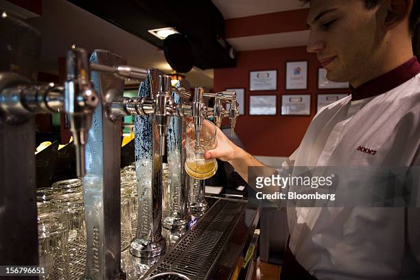 An employee prepares a glass tankard of beer behind the bar of a 100 Montaditos restaurant in Madrid, Spain, on Wednesday, Nov. 21, 2012. The...