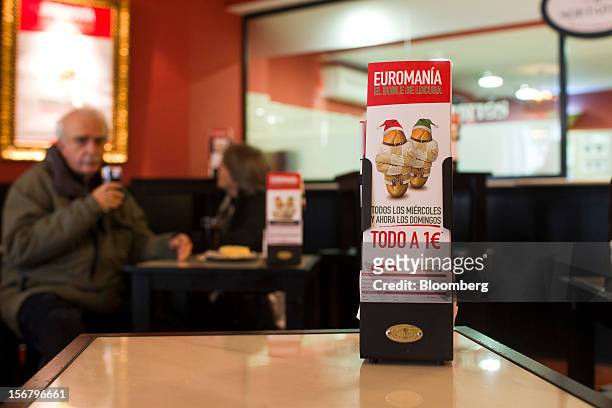 Customers eat at tables near promotional cards advertising one euro menus as part of "Euromania" Wednesdays in a 100 Montaditos restaurant in Madrid,...