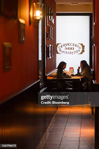 Customers sit and talk at a table in the window of a 100 Montaditos restaurant in Madrid, Spain, on Wednesday, Nov. 21, 2012. The Madrid-based chain...