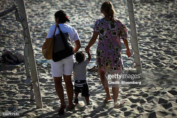 Maid, left, walks with a child in the sand at the Baixo Bebe beach playground in Rio de Janeiro, Brazil, on Monday, Nov. 19, 2012. With unemployment...