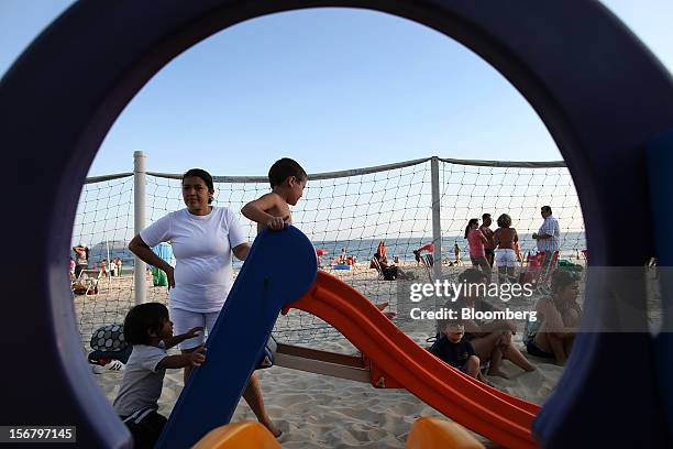 Maid watches children go down a slide at the Baixo Bebe beach playground in Rio de Janeiro, Brazil, on Monday, Nov. 19, 2012. With unemployment in...