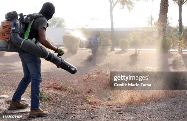 Alan Sibaja wears a head covering for sun protection while working with a leaf blower on July 24, 2023 in Phoenix, Arizona.While Phoenix endures...