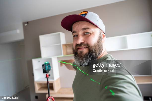 positive man pointing to the successful installed and leveled shelves on the wall using the professional laser level - leveled stock pictures, royalty-free photos & images