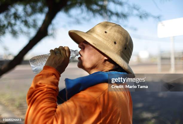 Yolanda Magana drinks water while taking a break from her work trimming trees ahead of monsoon season on July 24, 2023 in Phoenix, Arizona. While...