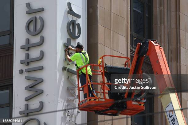 Worker removes letters from the Twitter sign that is posted on the exterior of Twitter headquarters on July 24, 2023 in San Francisco, California....
