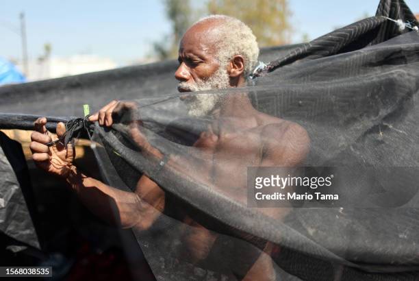 Rick White makes an adjustment to his tent in a section of the 'The Zone', Phoenix's largest homeless encampment, on July 24, 2023 in Phoenix,...