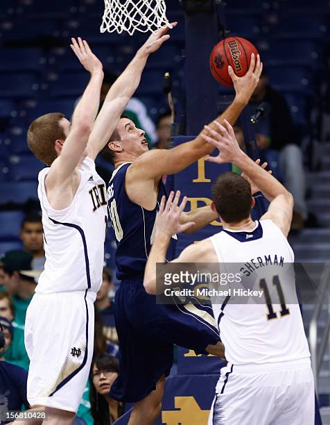 Nemanja Mikic of the George Washington Colonials puts up a layup as Scott Martin of the Notre Dame Fighting Irish and Garrick Sherman of the Notre...