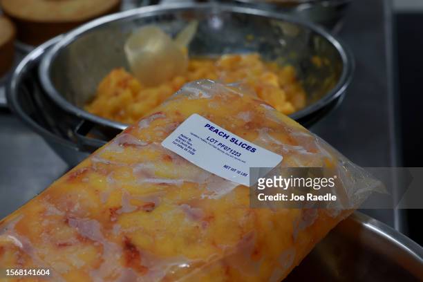Maria Garcia, a Pearson Farm baker, uses frozen peaches to make a peach cake from the fruit harvested off the trees at Pearson Farm on July 24, 2023...