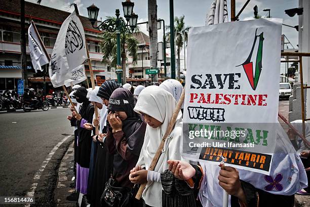 Muslim activists from Hizbut Tahrir Indonesia prays as protest during against the Israel and US governments as against Israeli air strikes on the...