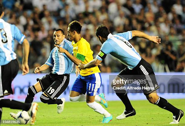Neymar, of Brazil fights for the ball with Pablo Guiñazú and Sebastian Dominguez of Argentina during the second leg of the Superclasico de Las...